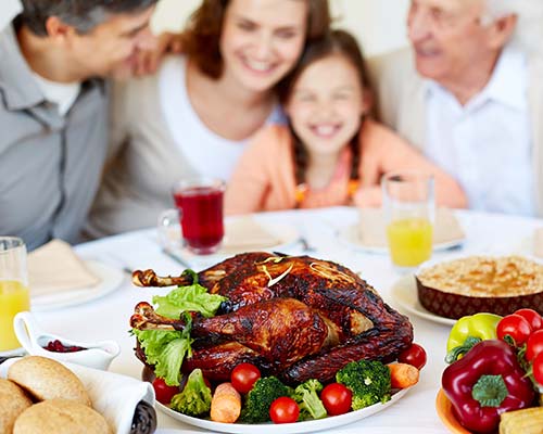 family sitting behind a table with a turkey on it